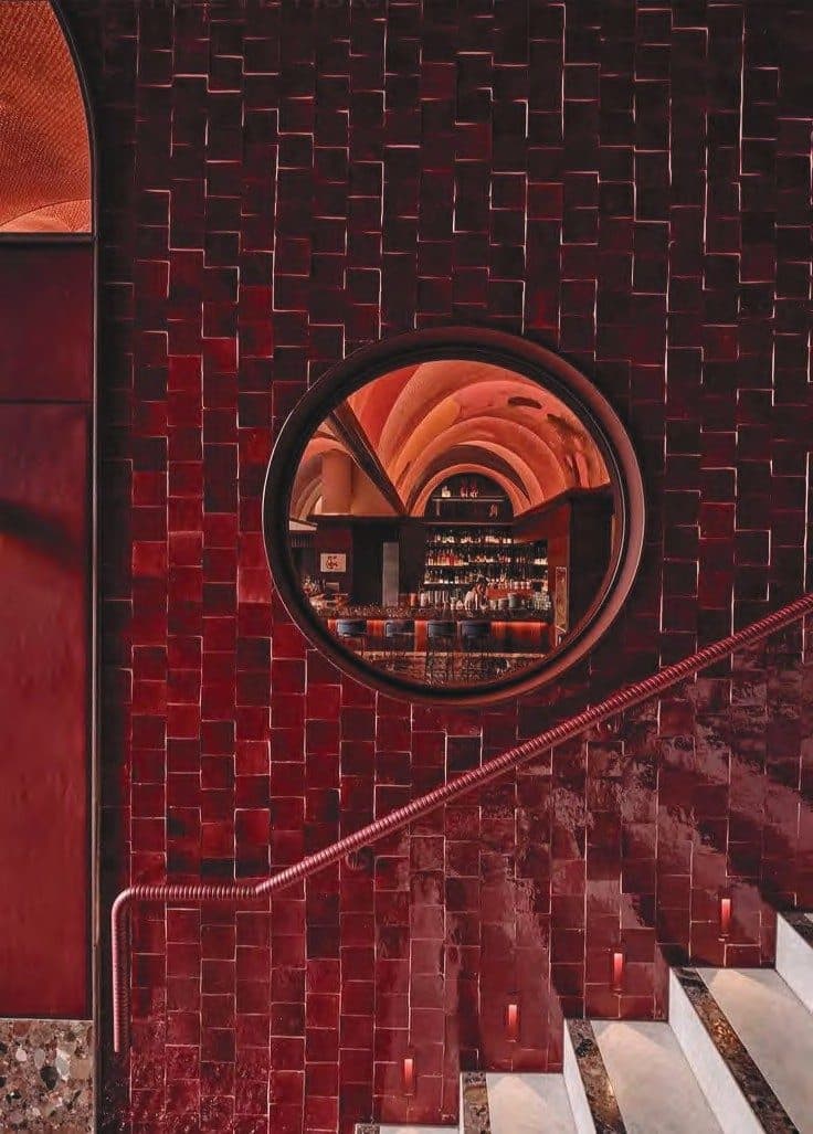 Tiled burgundy stairway and circular bar mirror
