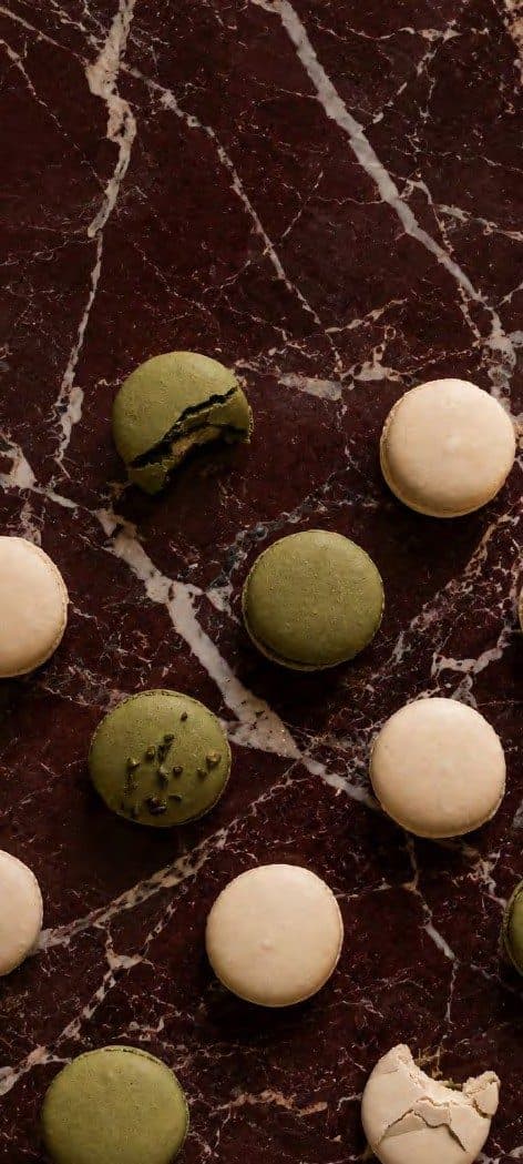 Pistachio and vanilla macarons on dark marble